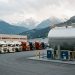 Camions poids lourds modernes stationnés dans un dépôt logistique près de Grenoble, avec une grande cuve de biocarburant et les montagnes alpines en arrière-plan.