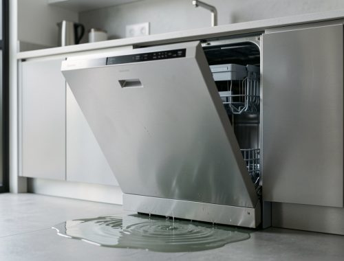 Lave-vaisselle moderne ouvert dans une cuisine, avec une petite fuite d’eau au sol illustrant une panne après plusieurs années d’utilisation.